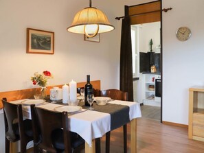 A dining area with a table set for four, a lamp, a clock, and a framed picture on the wall.