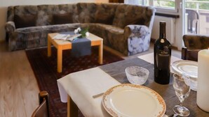 Una sala de estar con un sofá estampado, una mesita con una botella de vino, una vela y un vaso.
