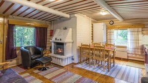 A cozy cabin interior with a fireplace, wooden dining table, and chairs.