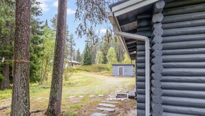 A log cabin with a stone pathway leading to a small shed.