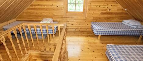 Una baita di legno con una camera da letto in soppalco, una scala in legno e una finestra che offre luce naturale.