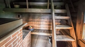 A wooden interior with a brick wall, wooden steps, and a small table with a bowl and utensils. - Meritähti by Interhome (Pöytyä)