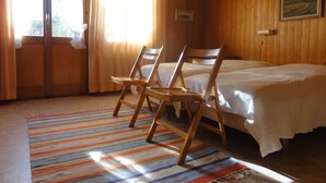 A room with two beds, wooden walls, a striped rug, and a painting on the wall.