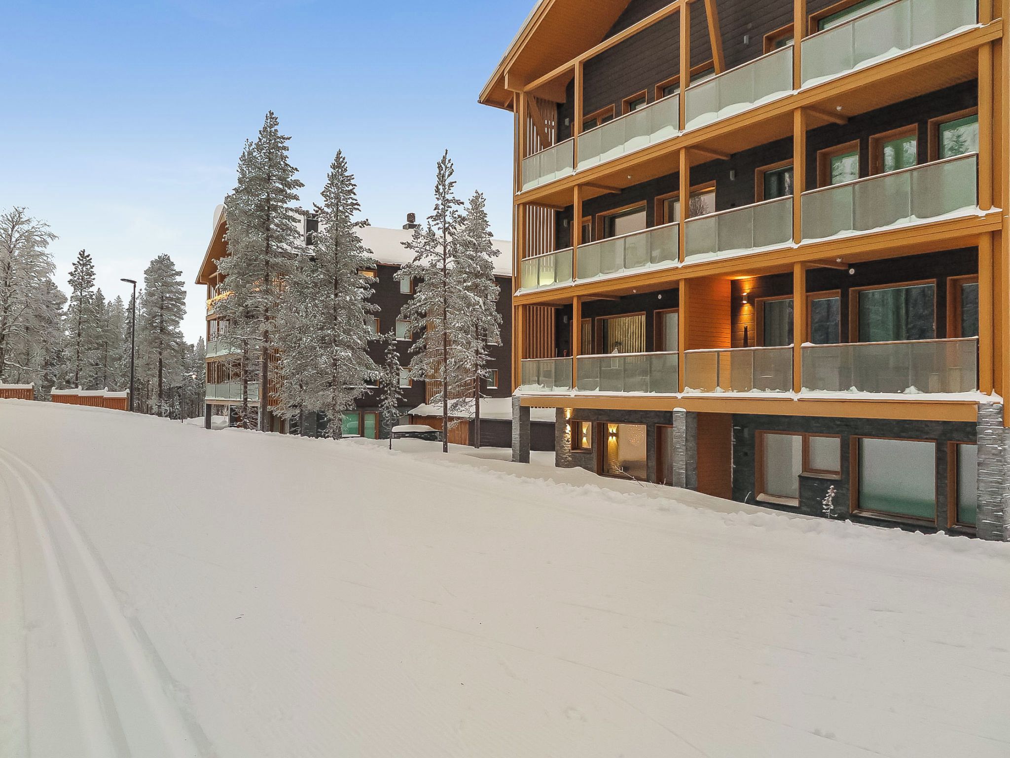 Een meerhoog hotel met balkons, omgeven door met sneeuw bedekte bomen.