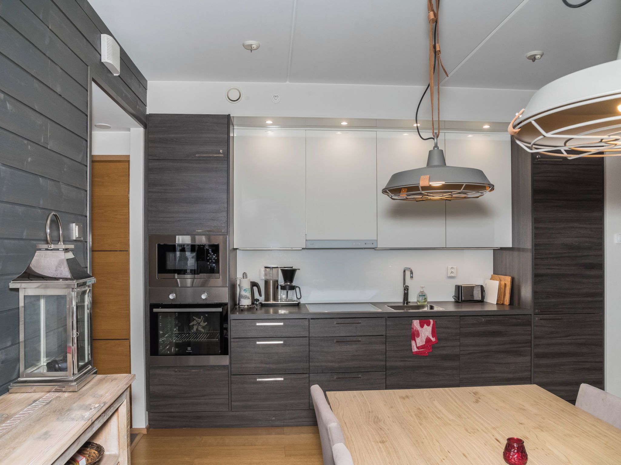 Una cocina moderna con armarios de madera oscura, electrodomésticos de acero inoxidable y una mesa de comedor de madera.