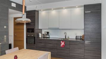 Una cocina moderna con armarios de madera oscura, horno empotrado, cafetera y lavamanos.