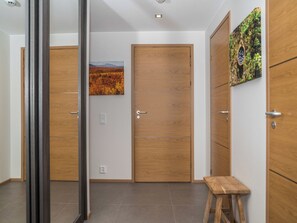 A hallway with wooden doors, a small stool, and a painting on the wall. - Levi hillside by Interhome (Kittilä)