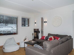 A modern living room with a gray sofa, a small table, and a bean bag chair. There are two windows with views of a snowy forest. - Levi hillside by Interhome (Kittilä)