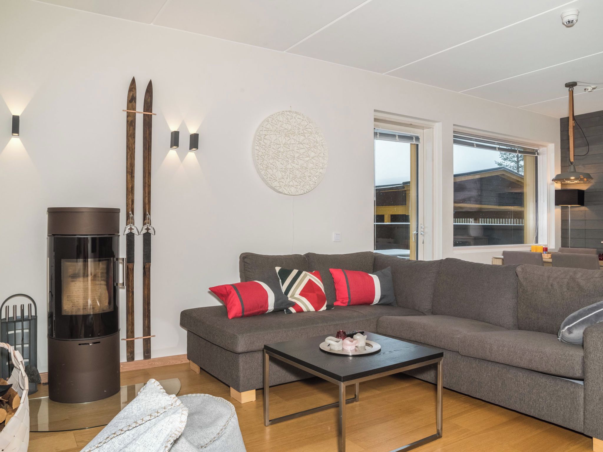 Een moderne woonkamer met een grijze bank, een salontafel en een open haard met houtkachel.