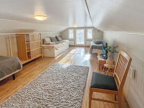 Un dormitorio acogedor en el ático con cama, sofá, silla de madera y televisor.