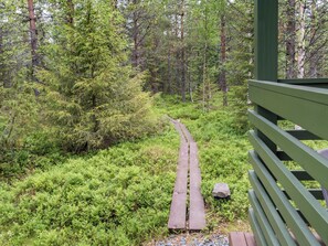 A wooden boardwalk through a dense forest with a green railing on the right. - Lupporanta by Interhome (Kuusamo)