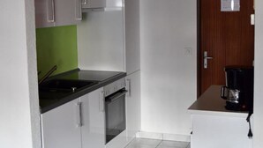 A compact kitchen with white cabinets, a black countertop, and a coffee maker. - Matten EG Süd by Interhome (Ried-Mörel)