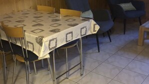 A dining area with a table covered in a patterned tablecloth, surrounded by chairs. - Matten EG Süd by Interhome (Ried-Mörel)