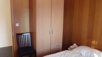 Ein Schlafzimmer mit einem Bett, einem Holzschrank und einem Stuhl.