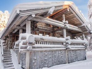 A log cabin with a snow-covered exterior, wooden beams, and a window.