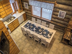 A log cabin interior with a dining table, chairs, a kitchen area, and a window with blinds. - Rukakieku by Interhome (Kuusamo)