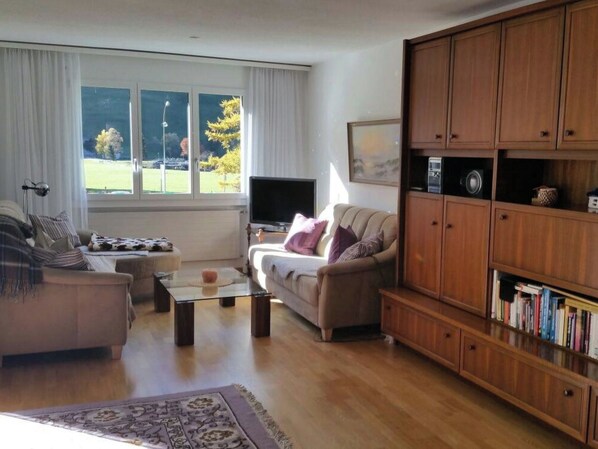 A living room with a sofa, a coffee table, a television, and a bookshelf.
