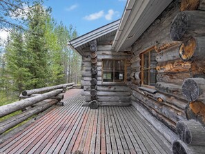A log cabin with a wooden deck and a window.