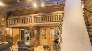 A log cabin interior with a fireplace, wooden furniture, and a stone accent wall. - Rukasaukko by Interhome (Kuusamo)