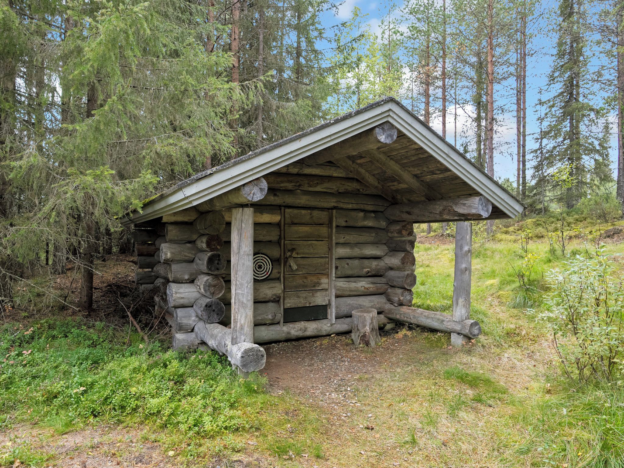 Eine rustikale Holzhütte mit Satteldach, umgeben von dichtem Wald.