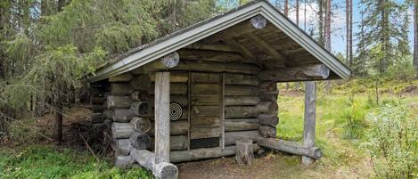Eine rustikale Holzhütte mit Satteldach, umgeben von dichtem Wald.