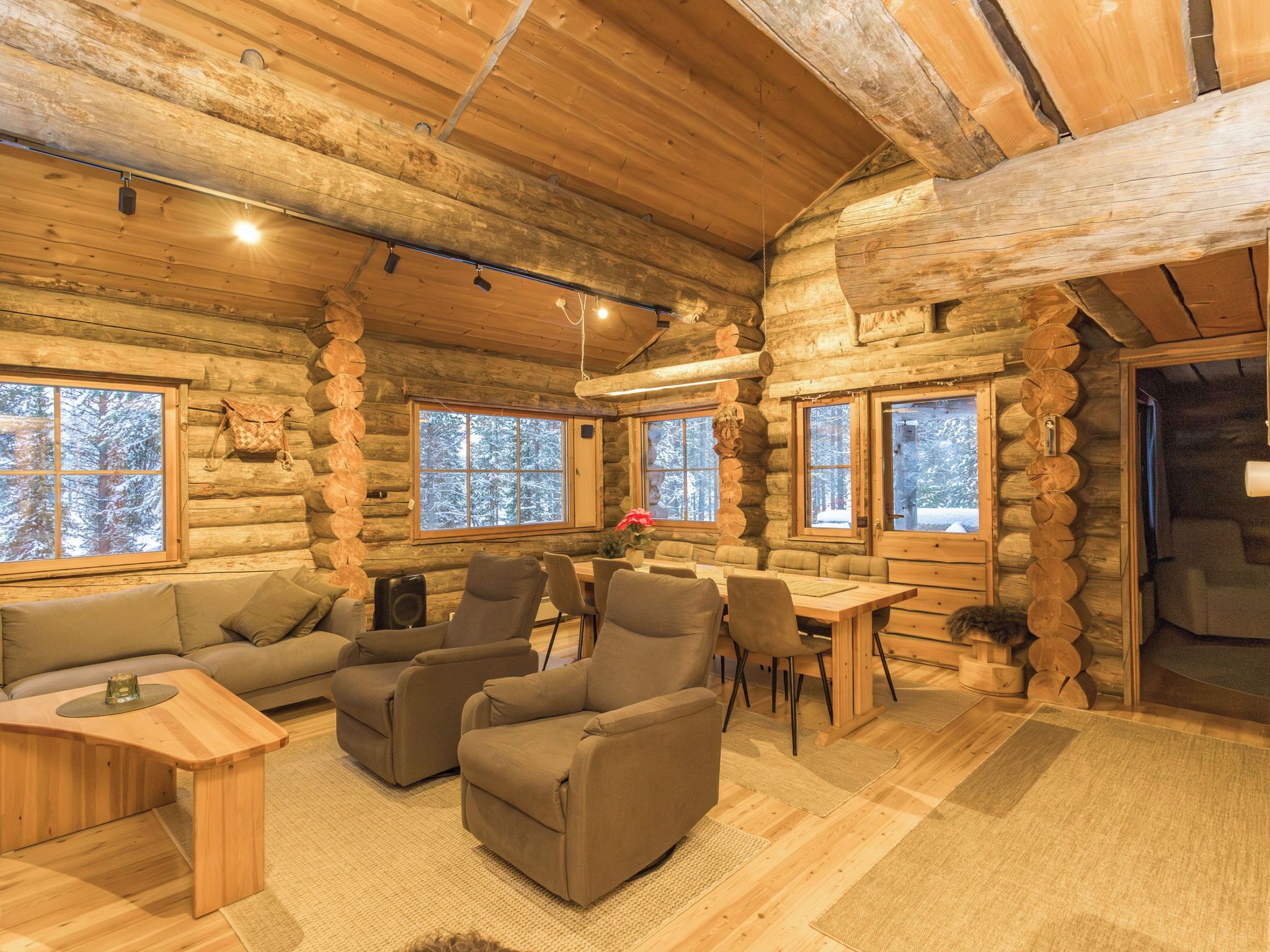 L’intérieur d’une cabane en rondins, avec un coin salon accueillant, des murs en bois et de grandes fenêtres.