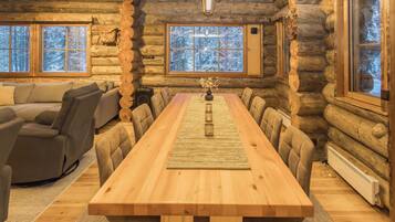 L’intérieur d’une cabane en rondins, avec une longue table à manger, un canapé et une cheminée.