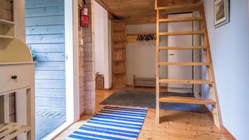 A wooden interior with a wooden ladder, a blue and white striped rug, and a white door.