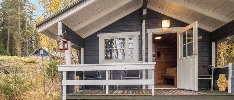 A cabin with a porch, a bench, and a door leading inside.
