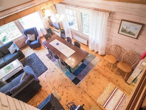 Een gezellig chaletinterieur met een eethoek, banken en een groot raam.