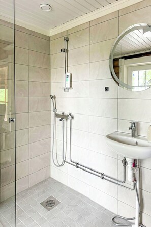 A modern bathroom with a glass shower enclosure, a wall-mounted sink, and a ceiling light.