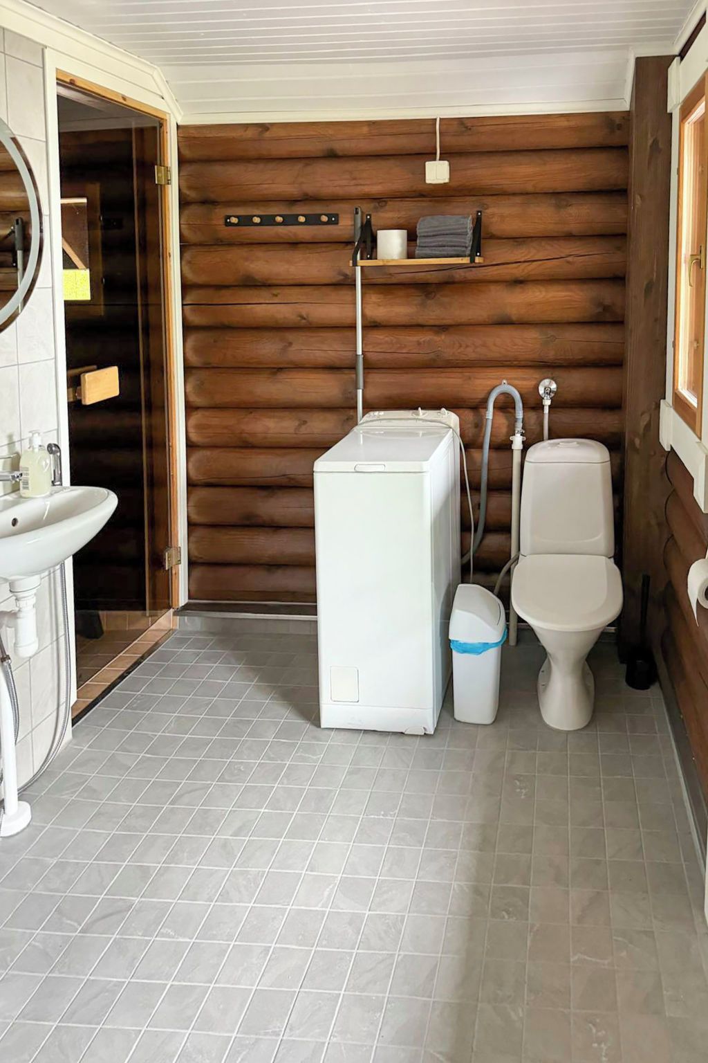 A compact bathroom with a washing machine, toilet, and sink.