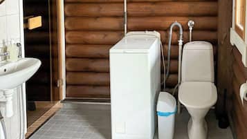 A compact bathroom with a washing machine, toilet, and sink.