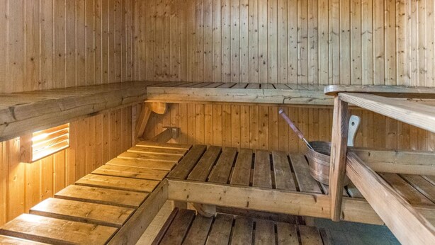 Uma sauna com bancos de madeira e um balde de metal.