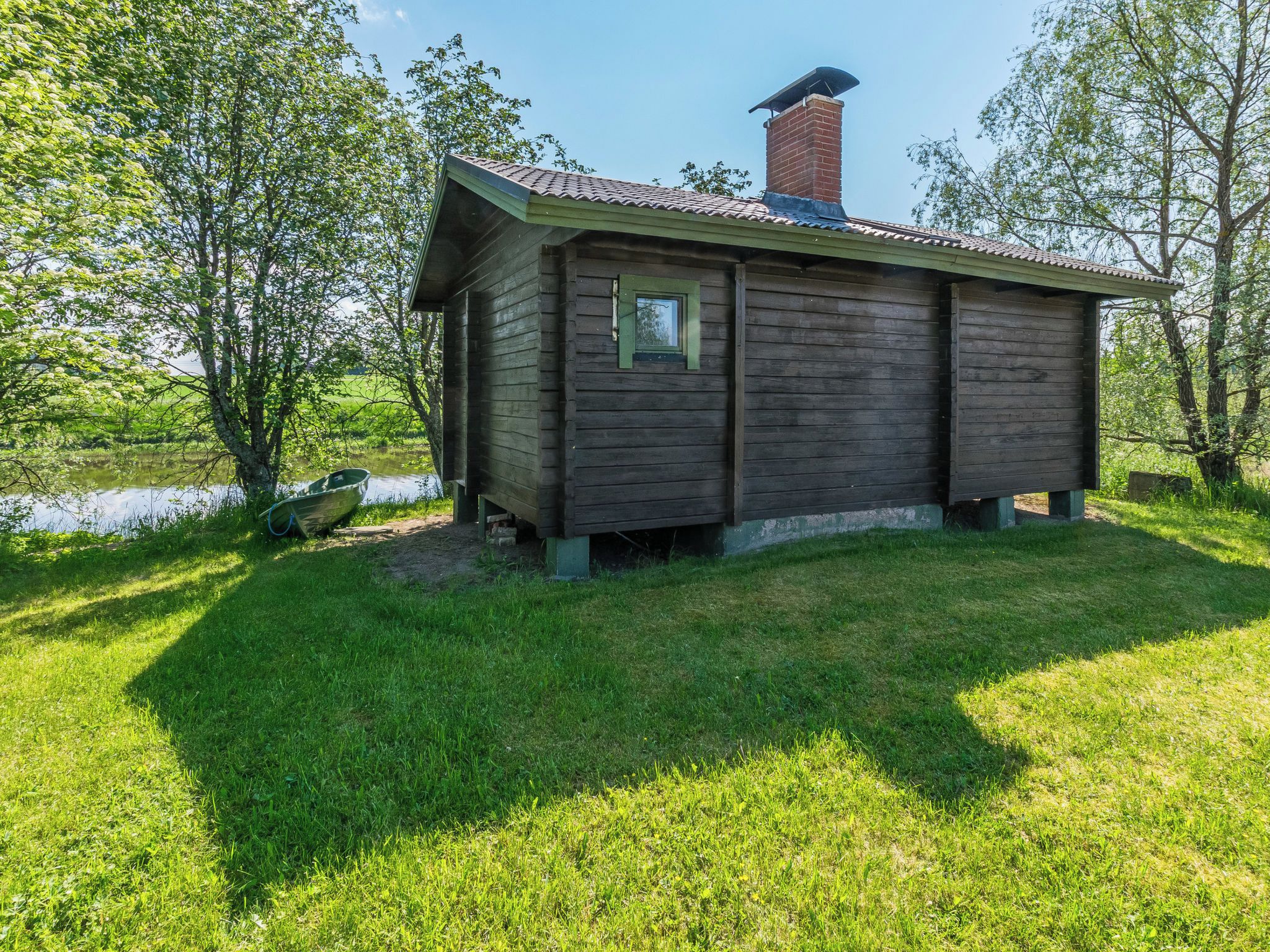 Puuinen mökki, jossa on savupiippu, pieni ikkuna ja ruohikkoon kasvanut piha.