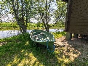 A green boat tied to a tree by a body of water, with a wooden structure in the background. - Kylämattila by Interhome (Loimaa)