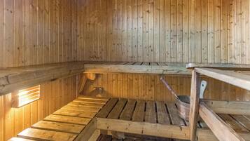 Un sauna avec des bancs en bois et un seau en métal.