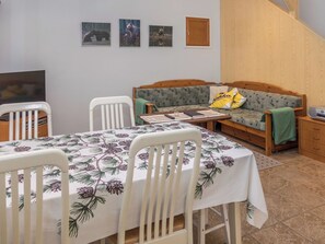 Una habitación acogedora con un sofá de madera, una mesa de comedor con sillas y un televisor.