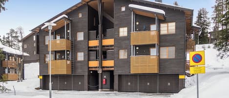 Un edificio de varios pisos con balcones, un telesilla y un cartel de prohibido estacionar.