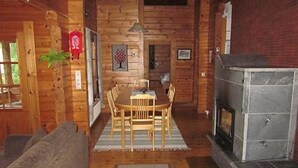 L’intérieur chaleureux d’un chalet comprend un coin repas, des murs en bois, une cheminée et un canapé.