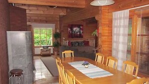 Une salle à manger en bois avec une table et des chaises, une fenêtre donnant sur un beau paysage et un luminaire suspendu.