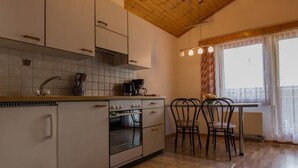 Una cuina amb armaris blancs, una estufa i una zona de menjador amb taula i cadires.
