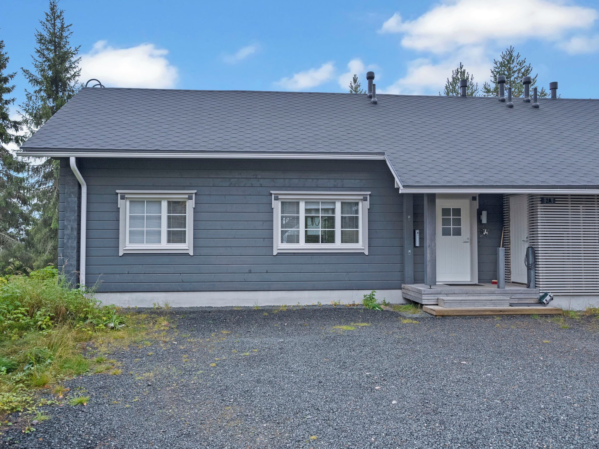A two-story house with a grey exterior, white window frames, and a grey roof.