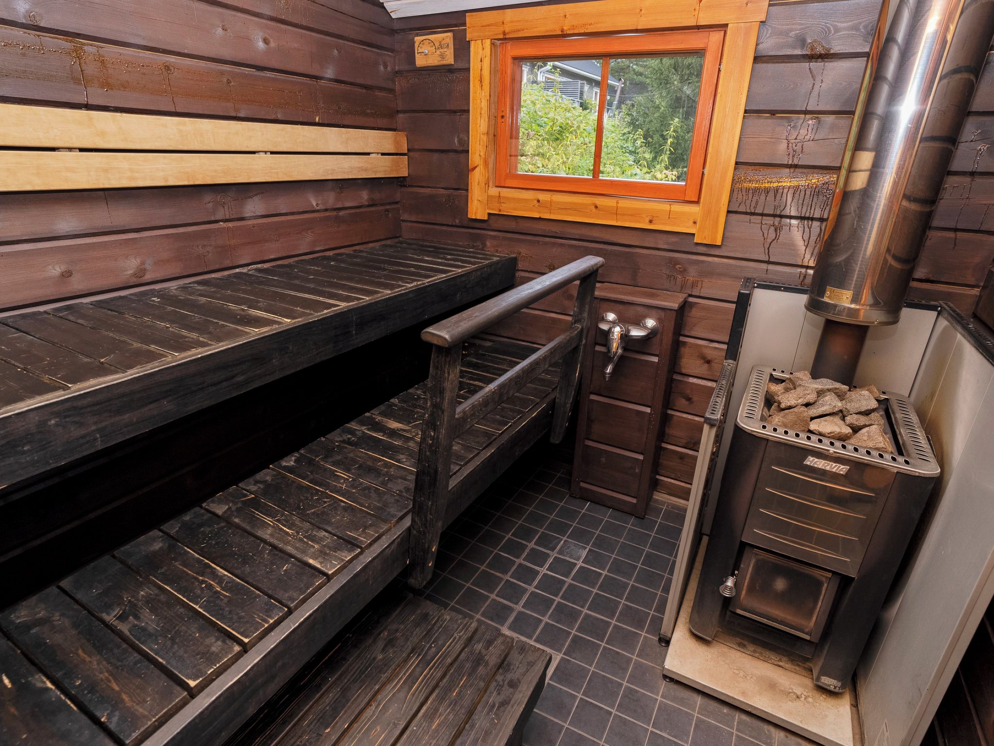 L’intérieur d’un chalet en bois, avec une cheminée, une fenêtre et un banc.