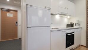 Une cuisine moderne avec des meubles blancs, un four encastré, un four à micro-ondes et une machine à café.