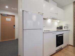Eine moderne Küche mit Kühlschrank, Backofen, Kaffeemaschine und Geschirrspüler.