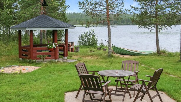 Un mirador con una mesa y sillas, una hamaca y vistas al lago.