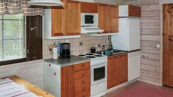 A compact kitchen with wooden cabinets, a microwave, a stove, and a refrigerator.