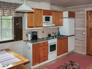 A compact kitchen with wooden cabinets, a microwave, a stove, and a refrigerator.