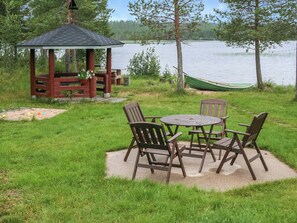A gazebo with a table and chairs in a grassy area near a lake. - Ahonlaita by Interhome (Posio)